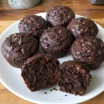 Double Chocolate Zucchini Muffins arranged on a white plate with a moist interior visible