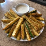 Baked Keto Zucchini Fries fanned on a plate with a ramekin of dip