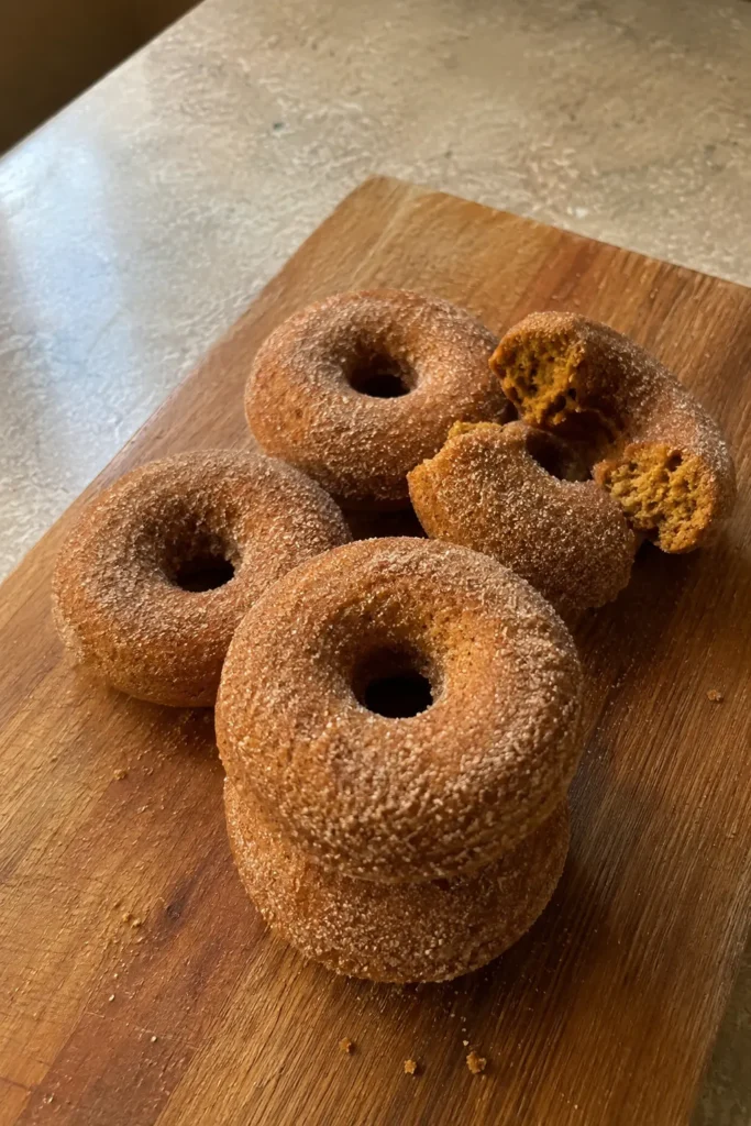 Pumpkin Spice Baked Donuts stacked on a wooden board for a fall breakfast