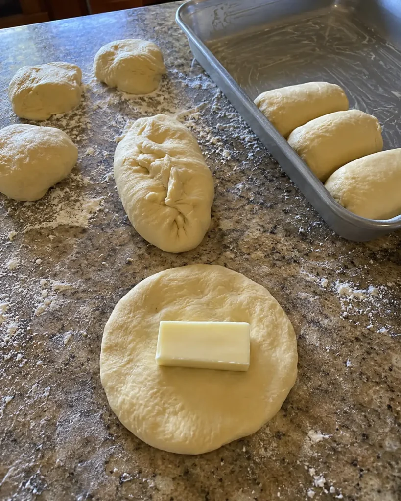 Dough being wrapped and sealed around mozzarella for stuffed bread rolls