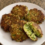 Crispy Zucchini Fritters with visible zucchini and herbs on a white plate