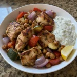 Bowl of GLP-1 high-protein dinner with lemon chicken, chickpeas, zucchini, and yogurt sauce