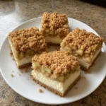 Homemade apple pie cheesecake bars showing graham crust and cinnamon apple layers