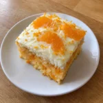 Square slice of Orange Creamsicle Cake on a white dessert plate